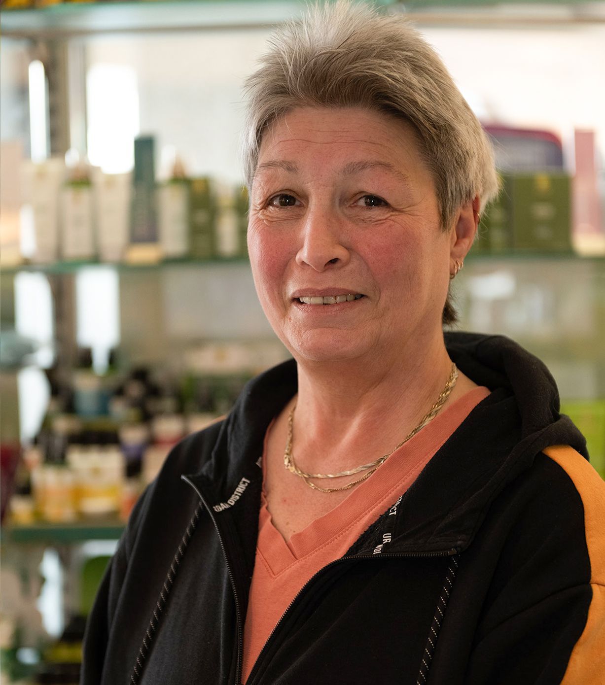 Eine Frau in einer schwarz-orangen Jacke lächelt in die Kamera