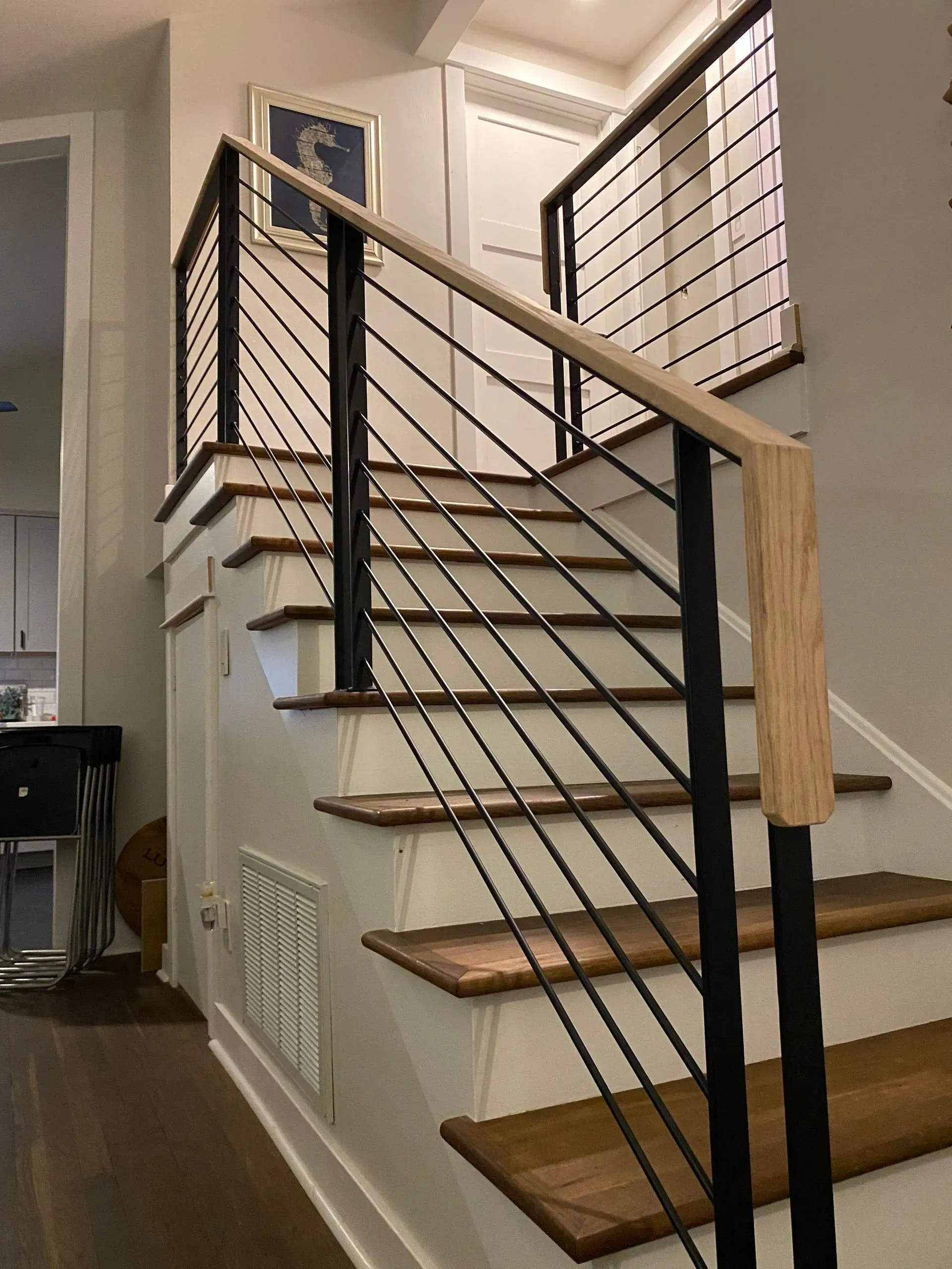 Staircase with wooden steps and a modern black metal railing. The walls are light gray.