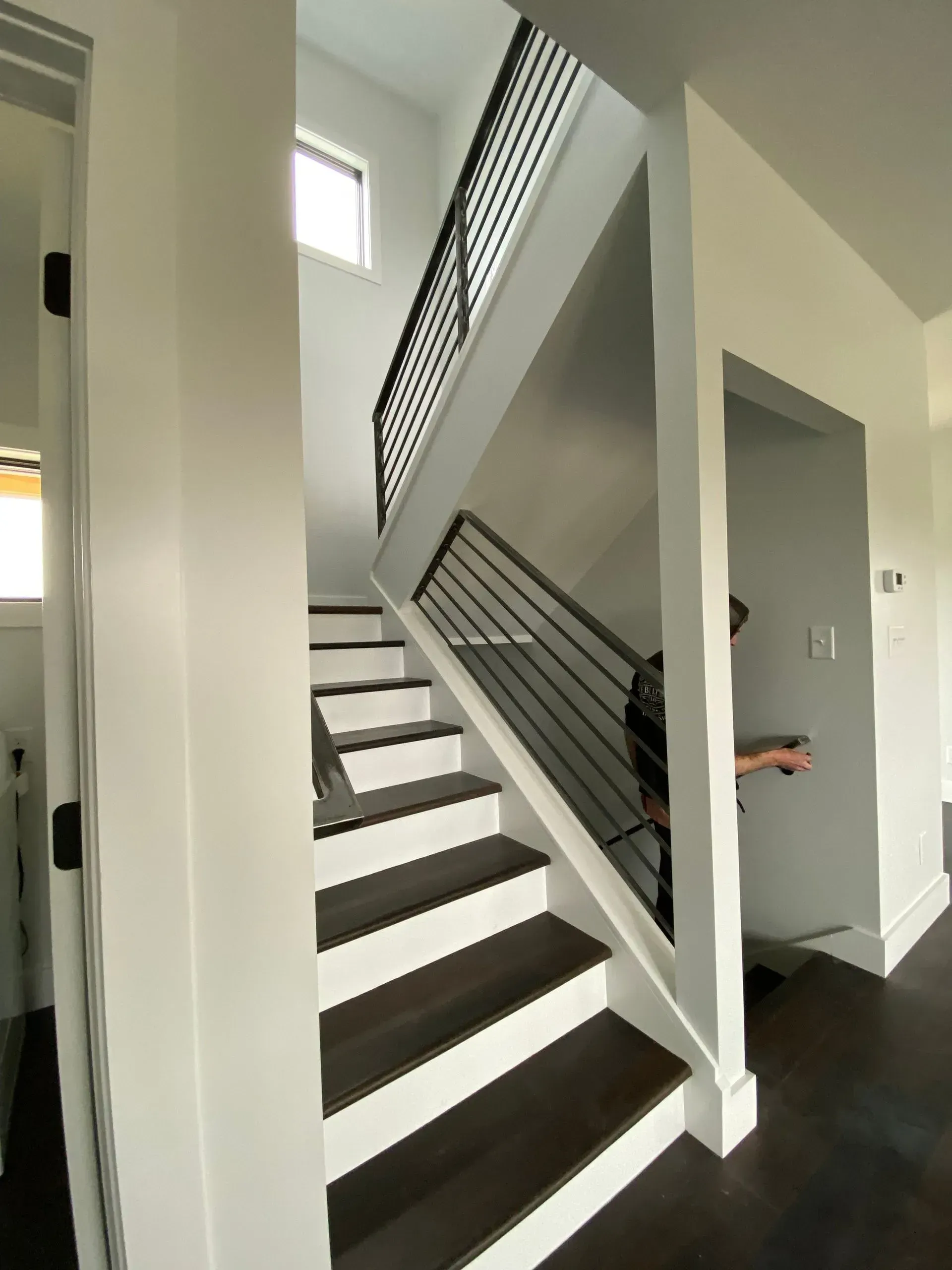 A modern staircase with dark wood steps, white risers, and black metal railings. 