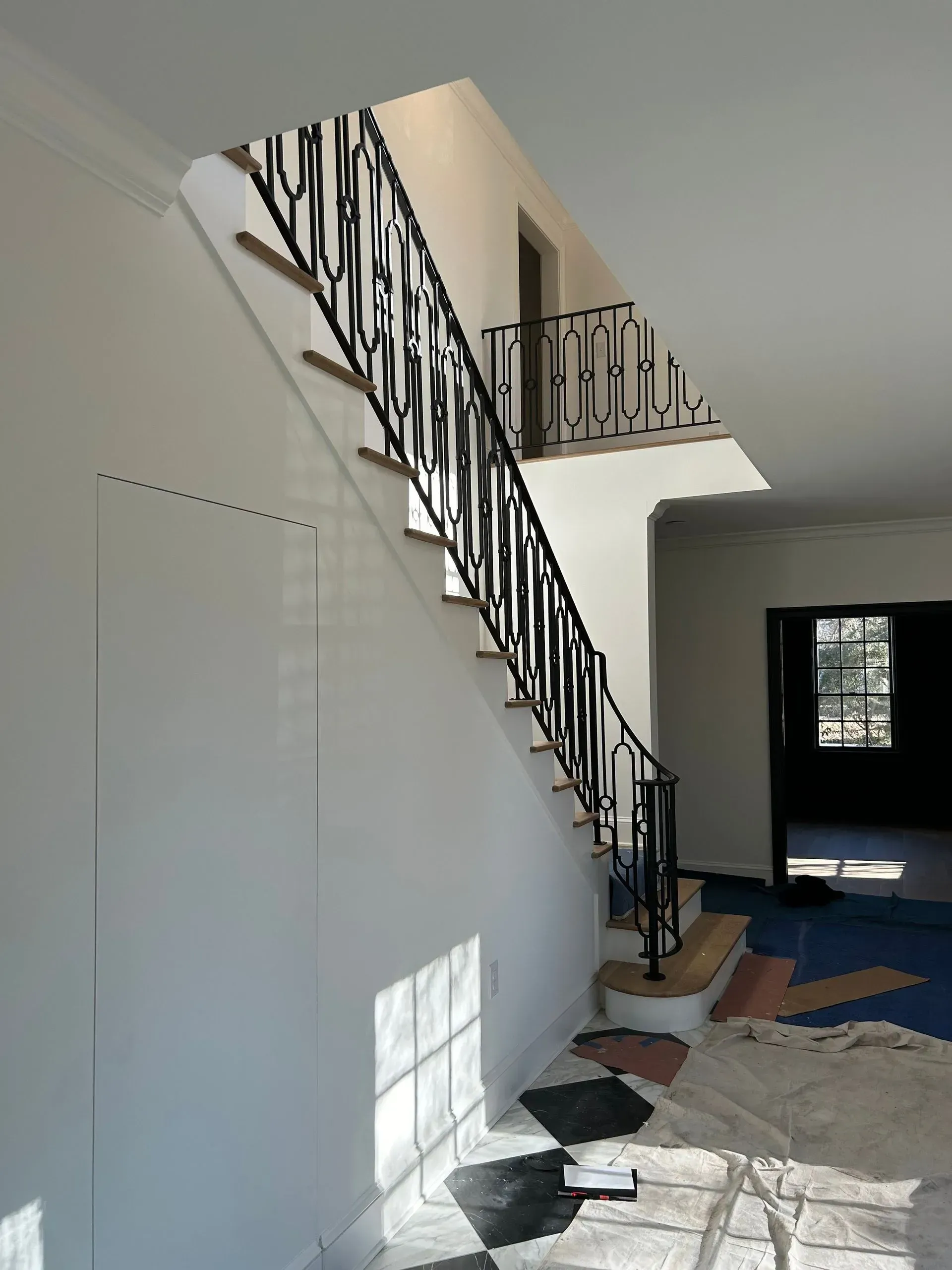 A staircase with black wrought iron railing ascends to a second story. 