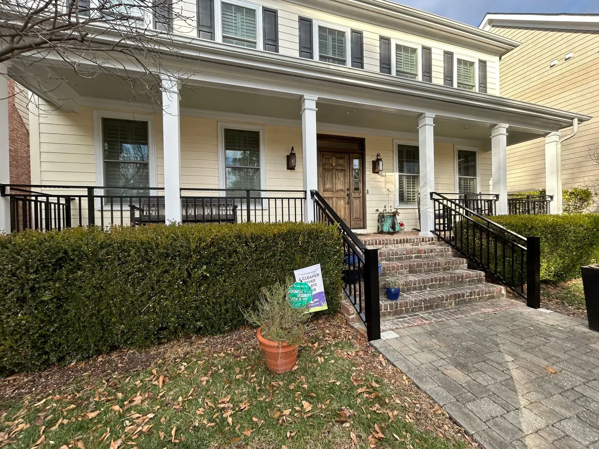 Two-story building with a porch supported by white columns. Black railing surrounds the porch. 