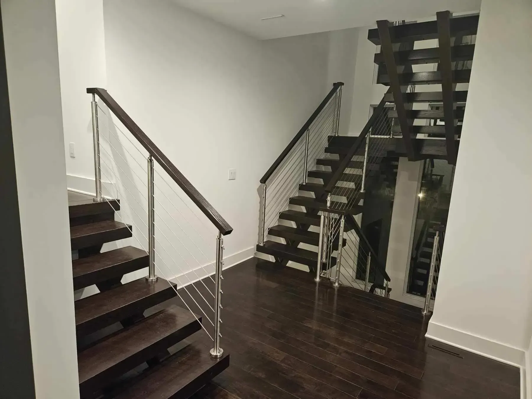 Dark wood staircase with metal railings, and white walls. 