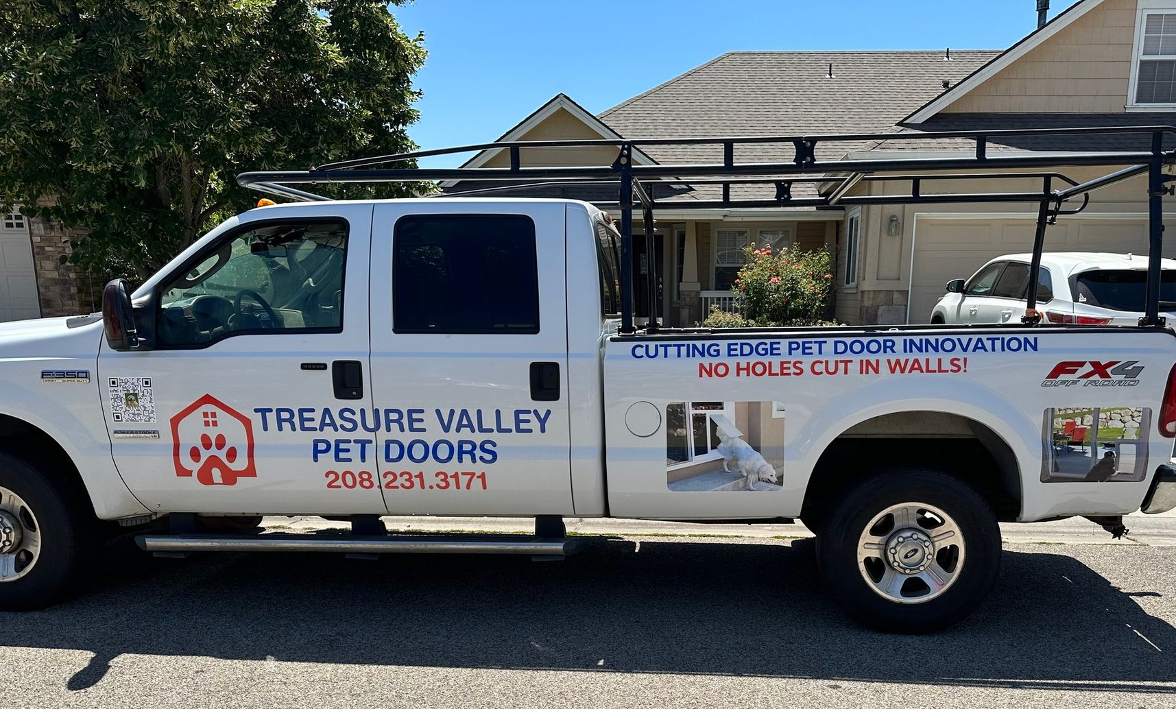 White pickup truck with Treasure Valley Pet Doors logo parked in front of a house.