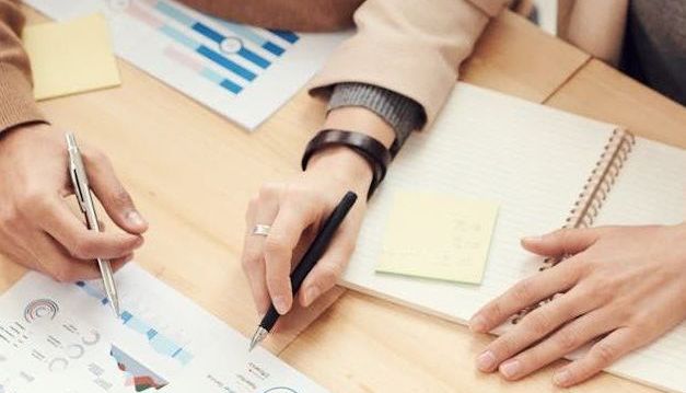 A group of people are sitting at a table looking at charts and graphs.