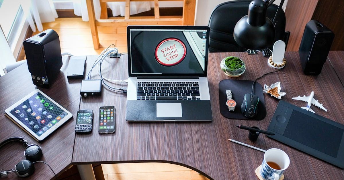 A laptop computer is sitting on top of a wooden desk surrounded by other electronic devices.
