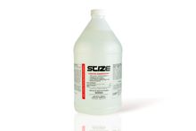 A bottle of scize sits on a rock near a river