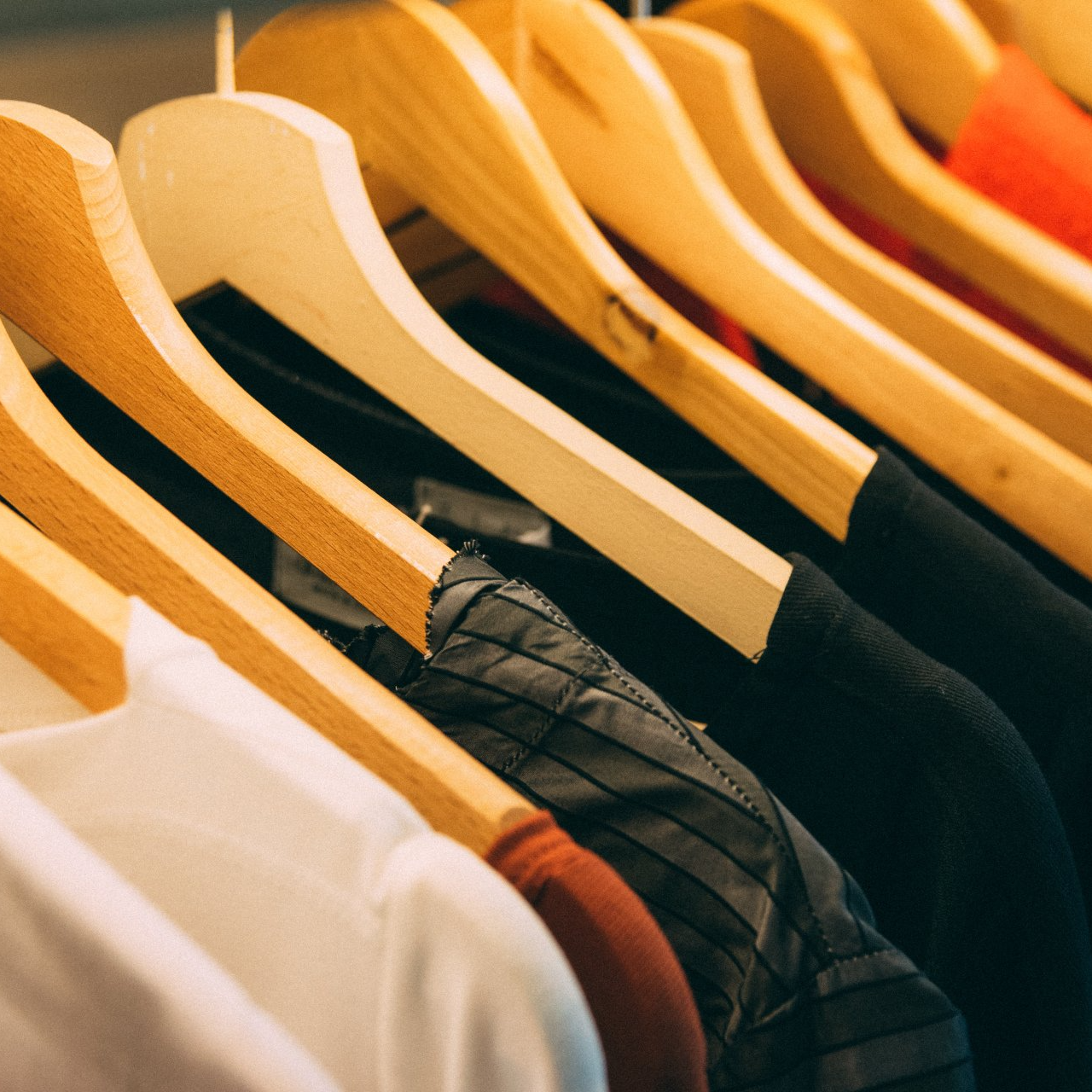 A row of wooden hangers with clothes hanging on them