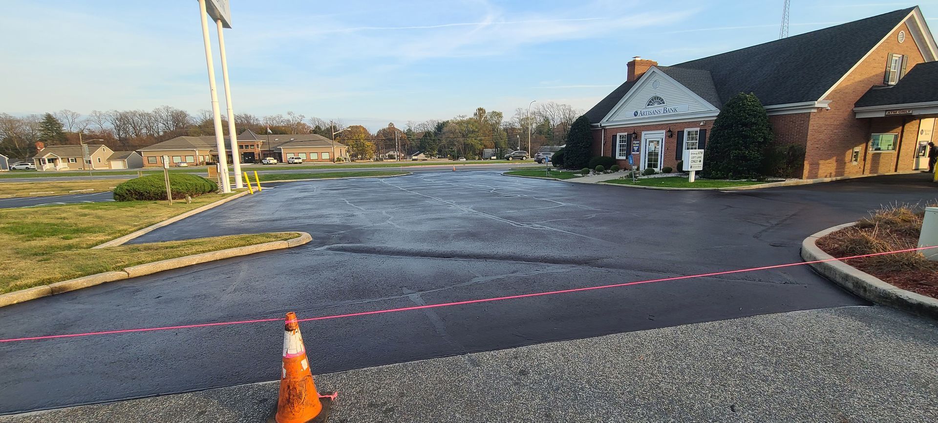 A man is painting a concrete driveway with a roller.
