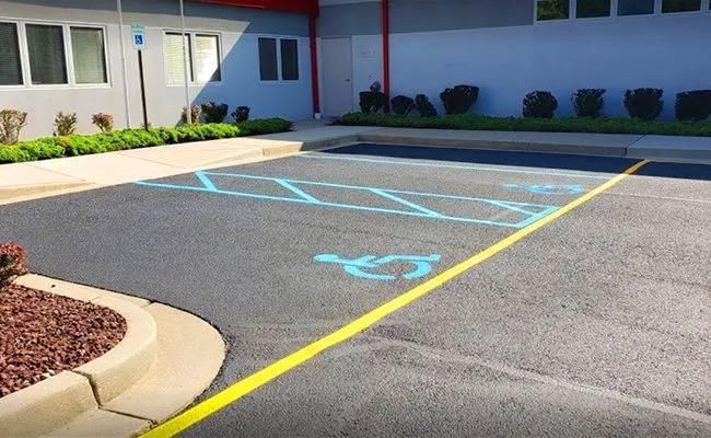 A man is painting a driveway with a roller.