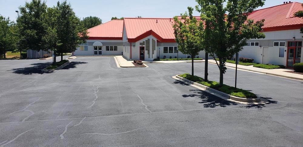 A man is painting a concrete driveway with a roller.
