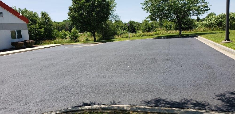 A man is standing next to a machine that is laying asphalt on a road.