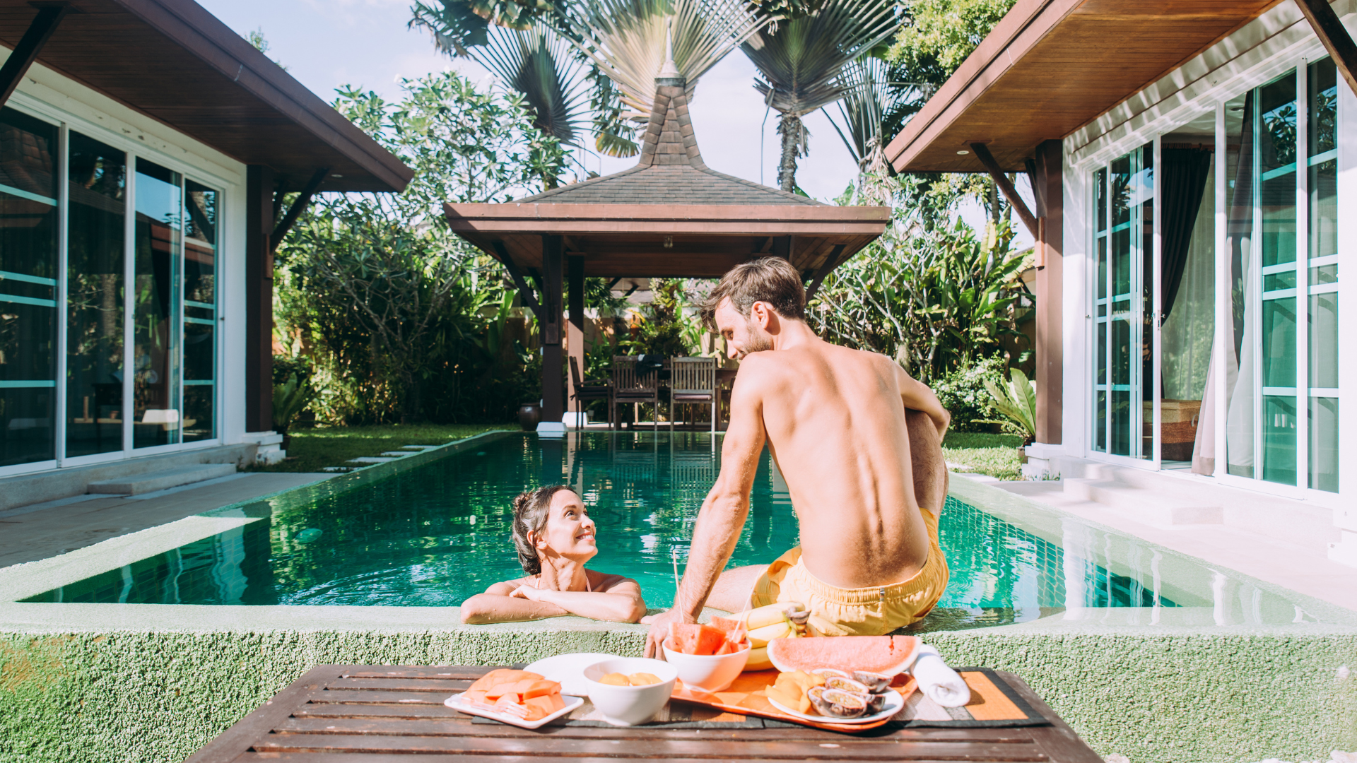A man and a woman are sitting next to a swimming pool.