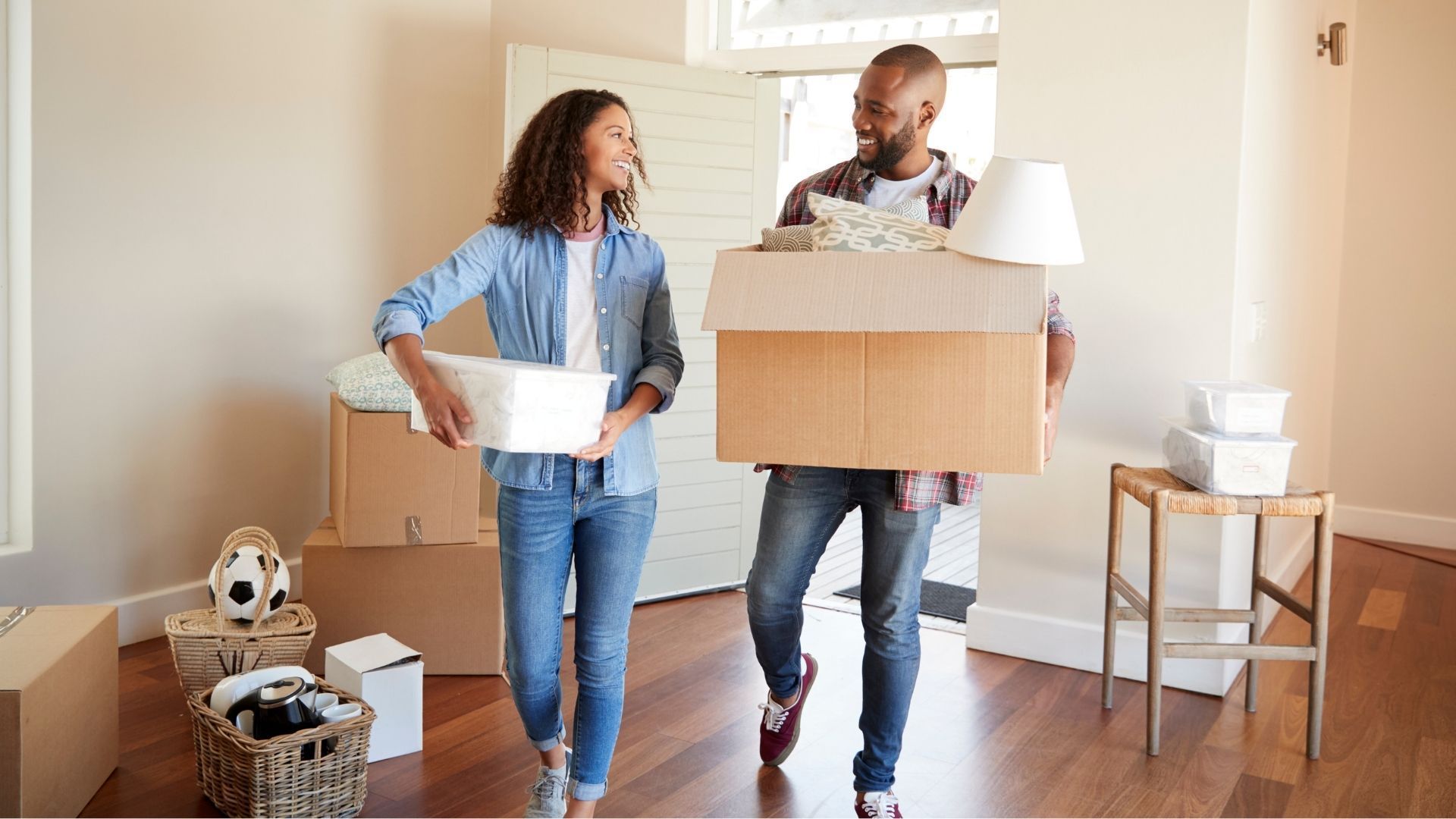 A man and a woman are carrying boxes into a new home.