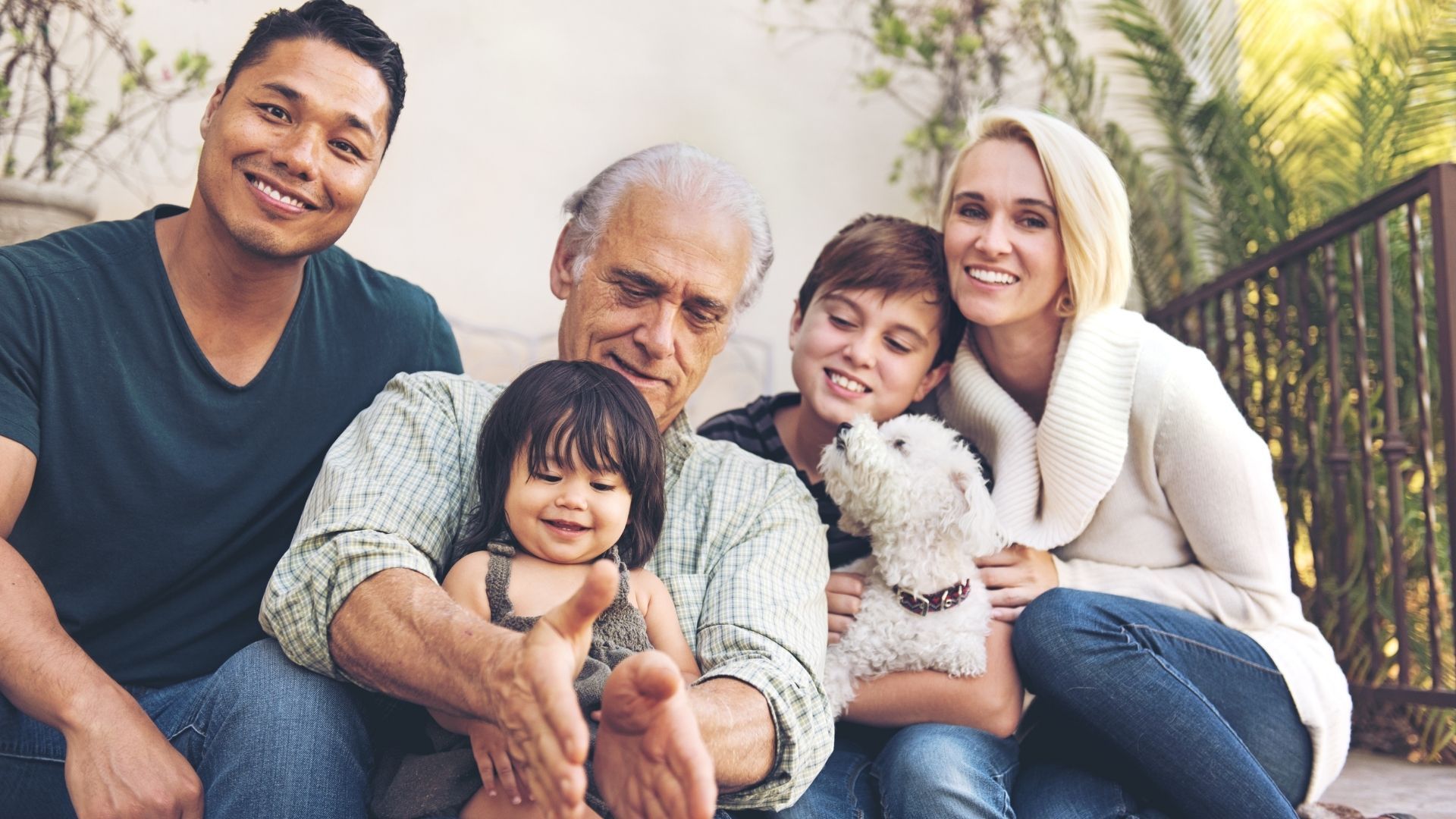 A family is posing for a picture while sitting on a porch.