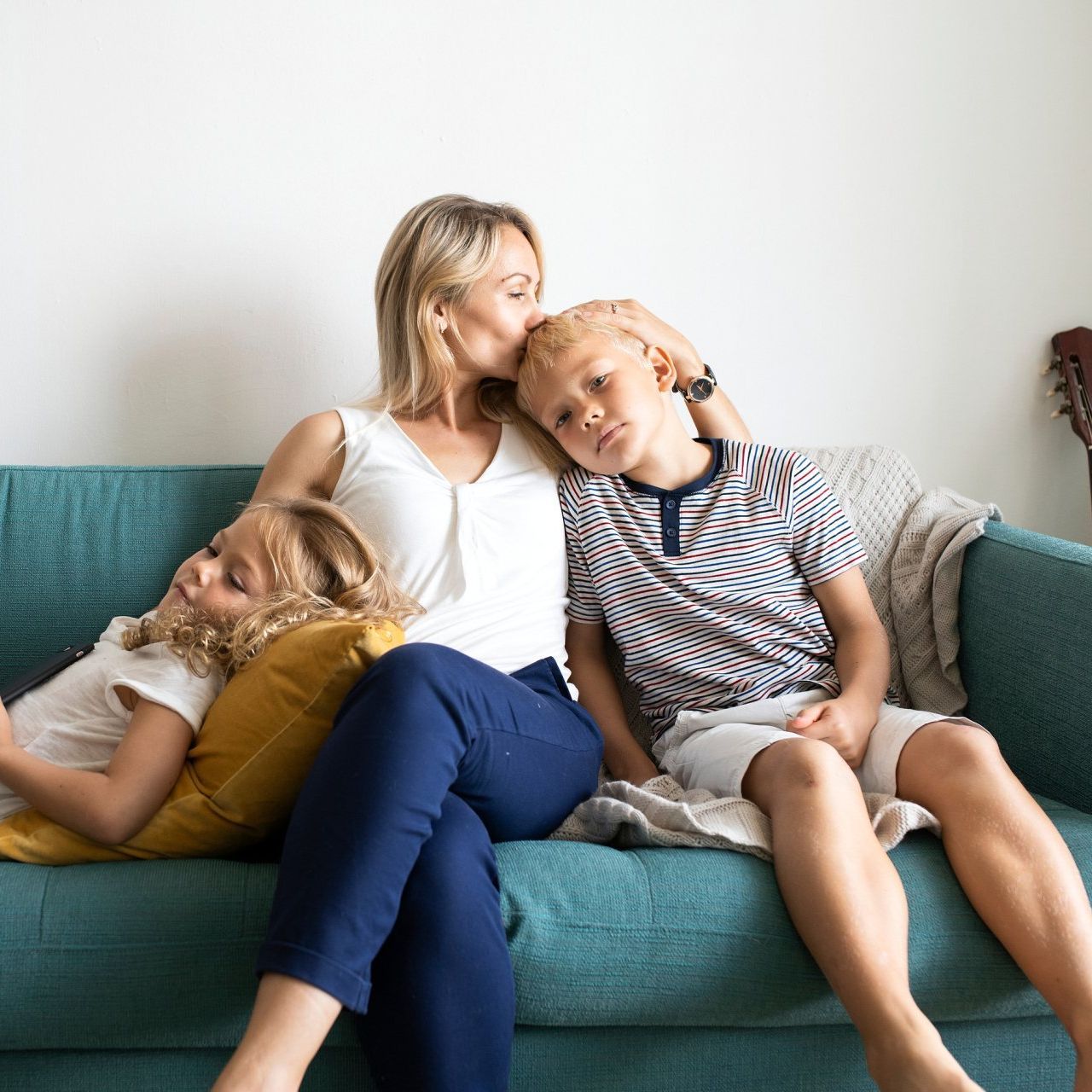 A woman and two children are sitting on a blue couch.