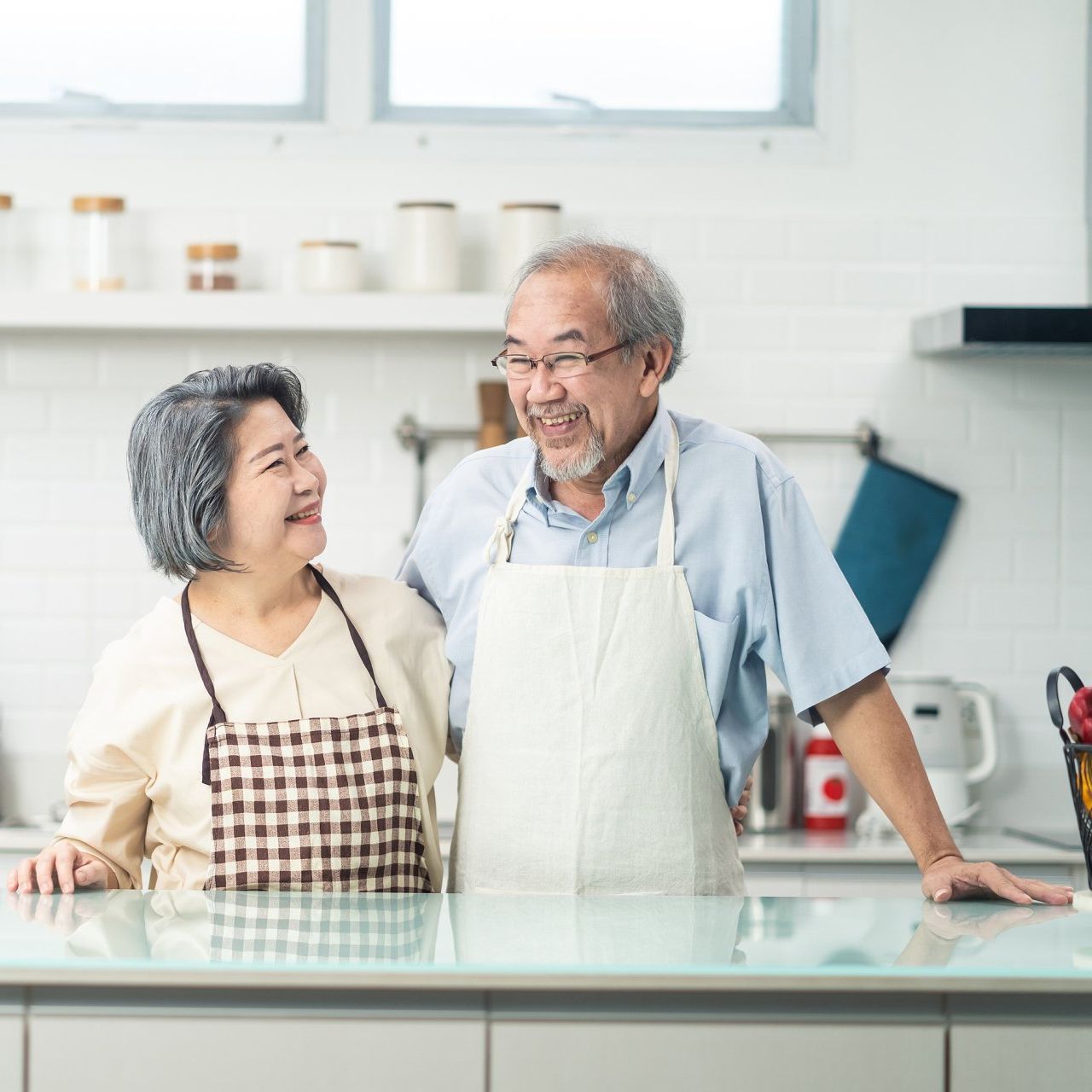 A man and a woman wearing aprons are standing in a kitchen