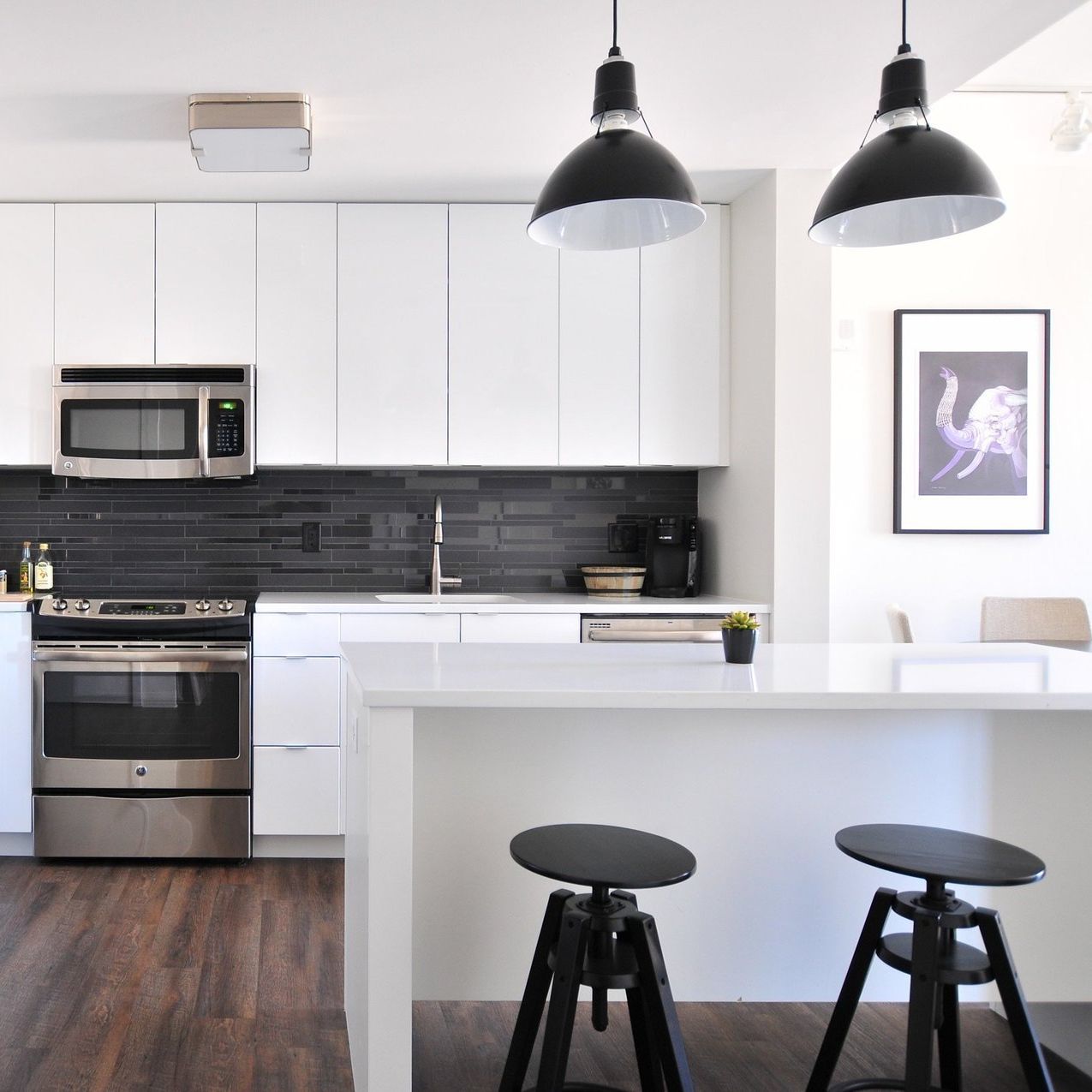 A kitchen with white cabinets and black stools