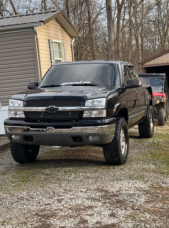 Black Chevy Silverado pickup truck parked outdoors on grass.