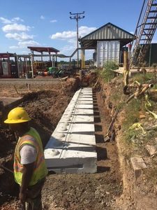 Construction site with a long trench and neatly placed concrete blocks forming the base of a retaining wall during a concrete block retaining wall service in Herriman, UT