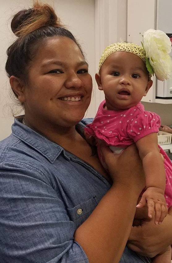 a woman is holding a baby in her arms and smiling .