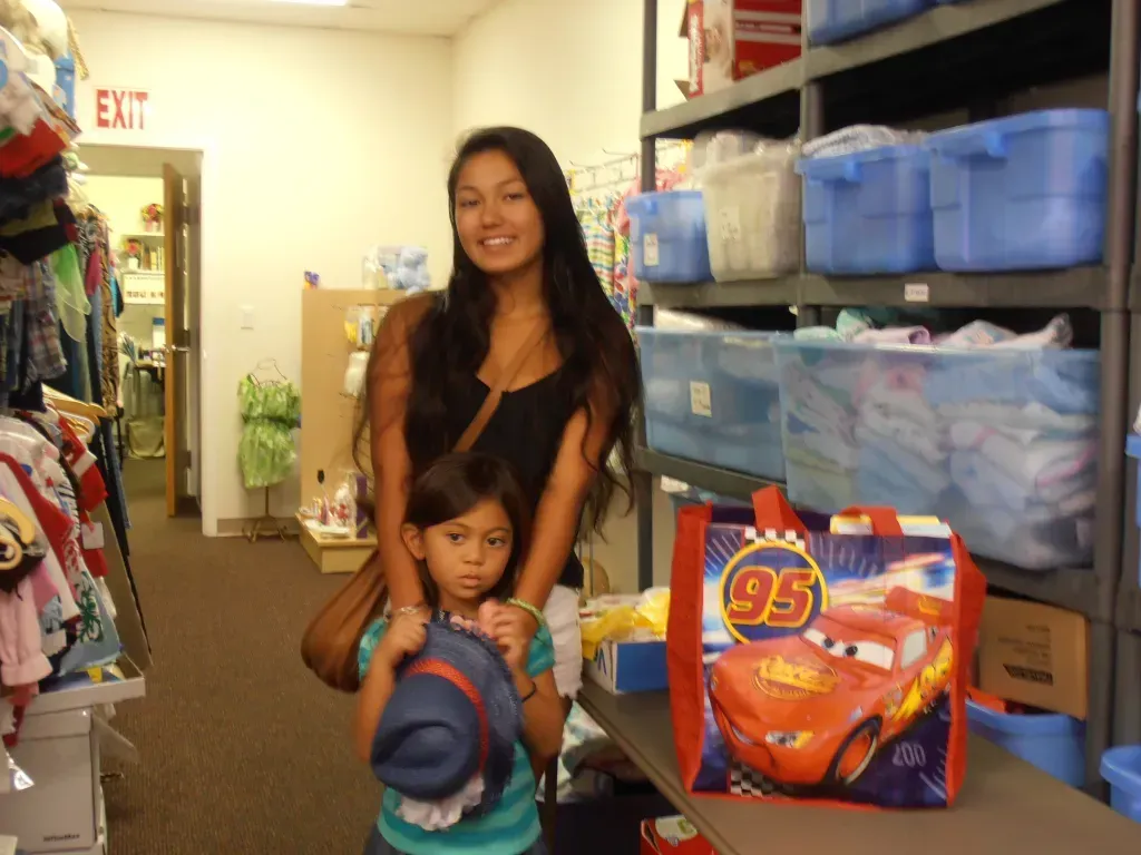 a woman holds a child 's hat in front of an exit sign