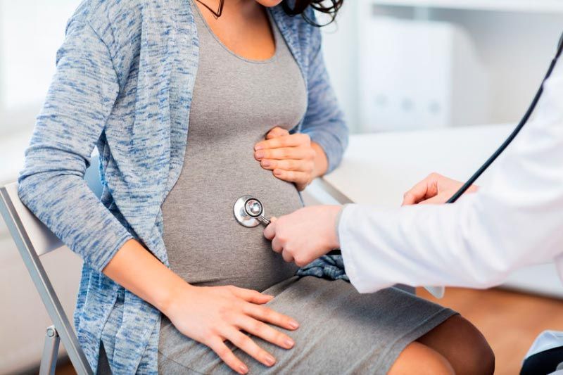 a pregnant woman is being examined by a doctor with a stethoscope .