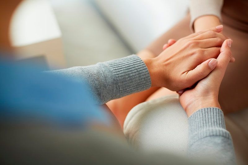 a woman is holding another woman 's hand while sitting on a couch .