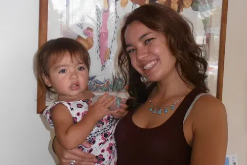 a woman is holding a little girl in her arms and smiling .
