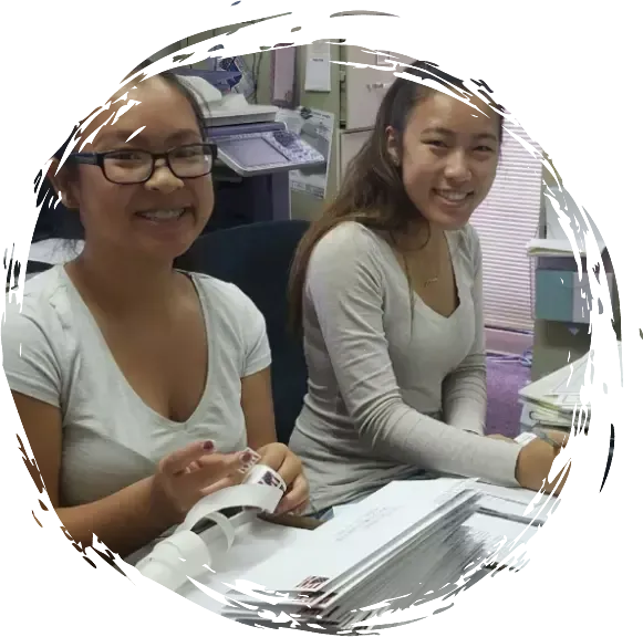 two women are sitting at a desk and smiling for the camera