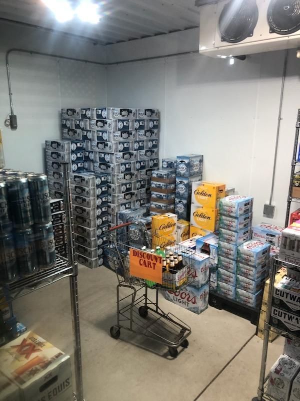 A room filled with lots of boxes of beer and a shopping cart.