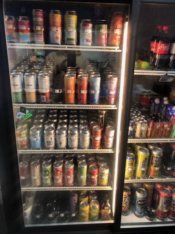 A refrigerator filled with cans of soda including coca cola