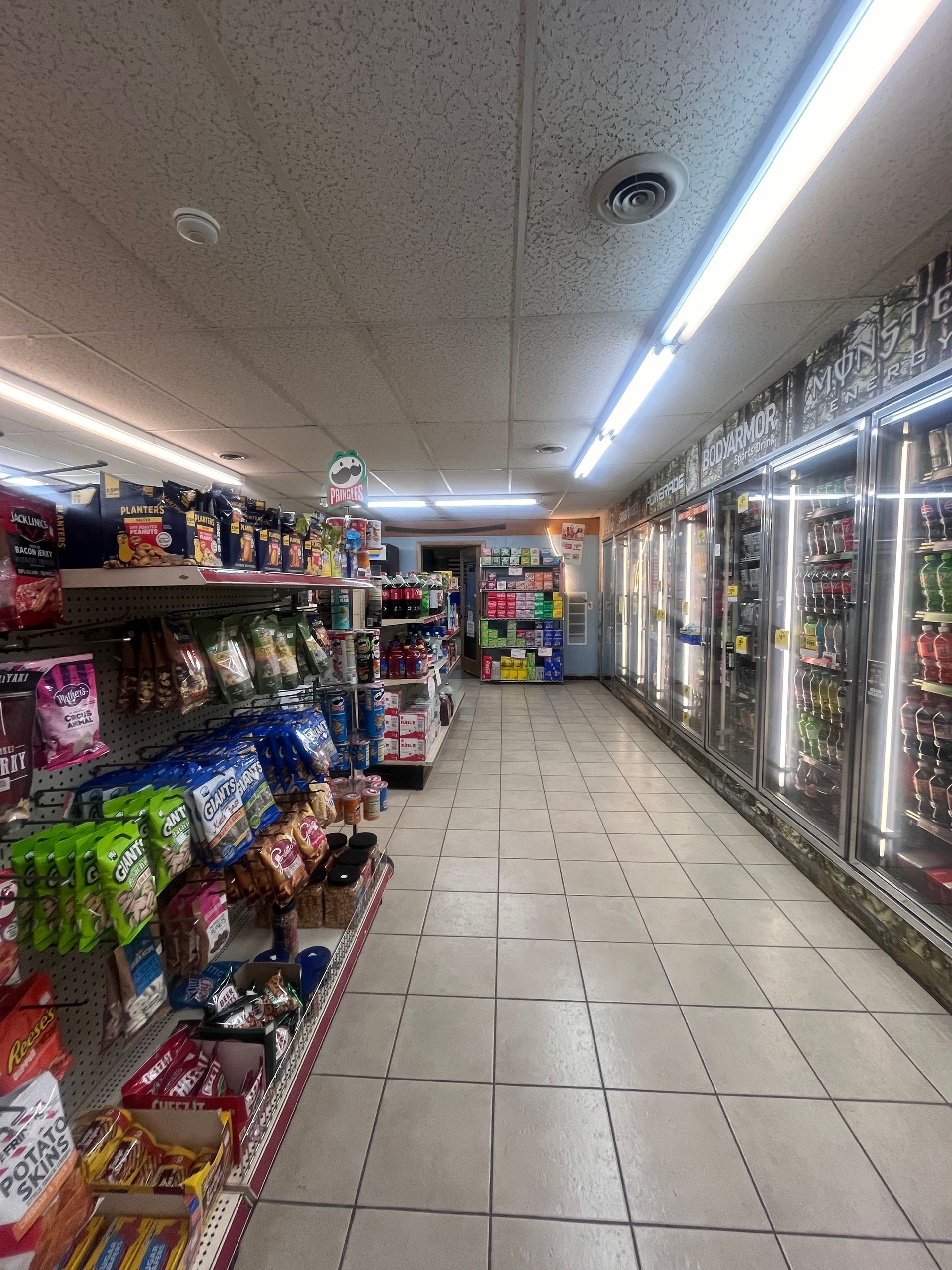 The inside of a grocery store with a lot of shelves and coolers.