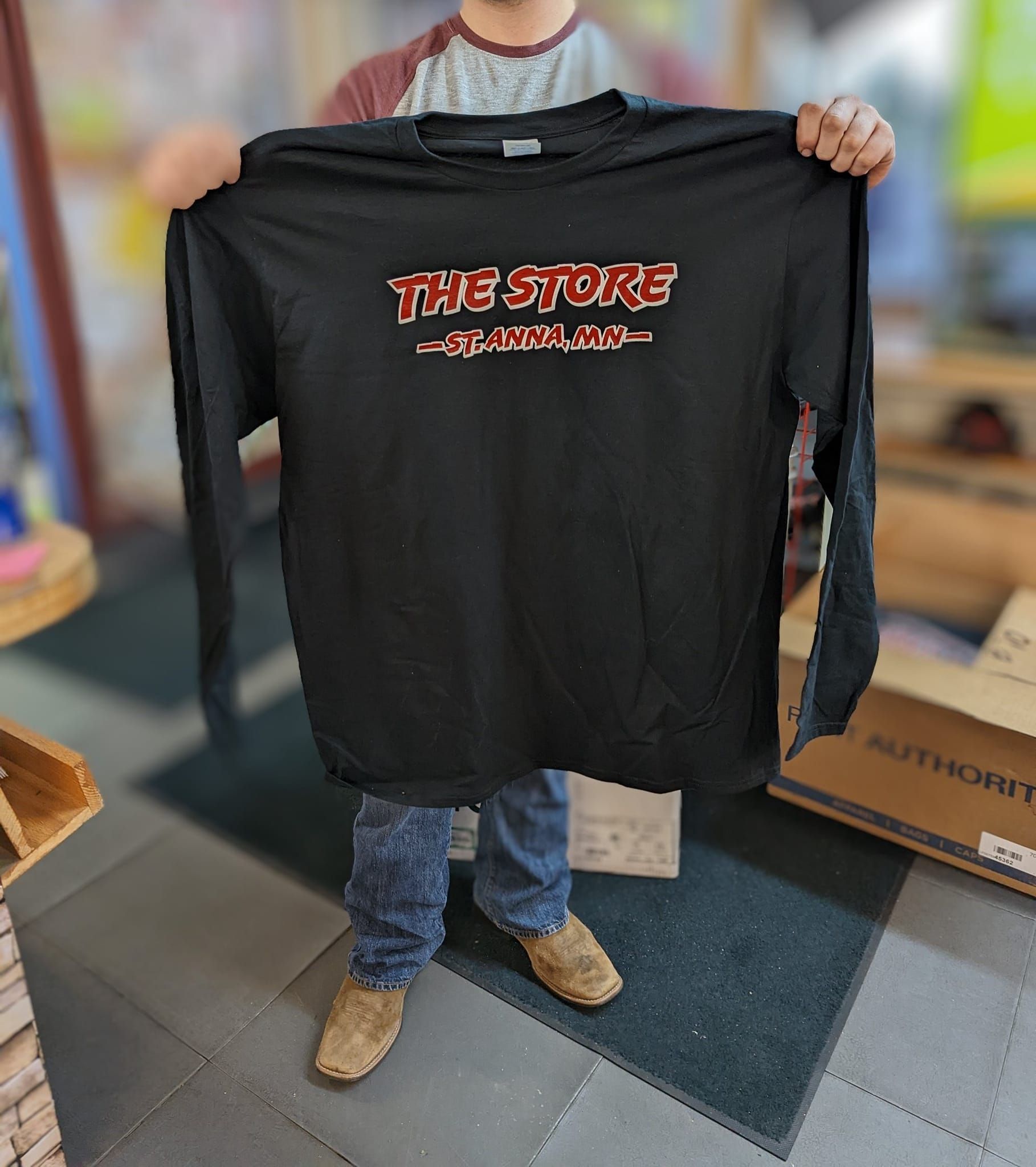 A man is holding a black t-shirt that says the store