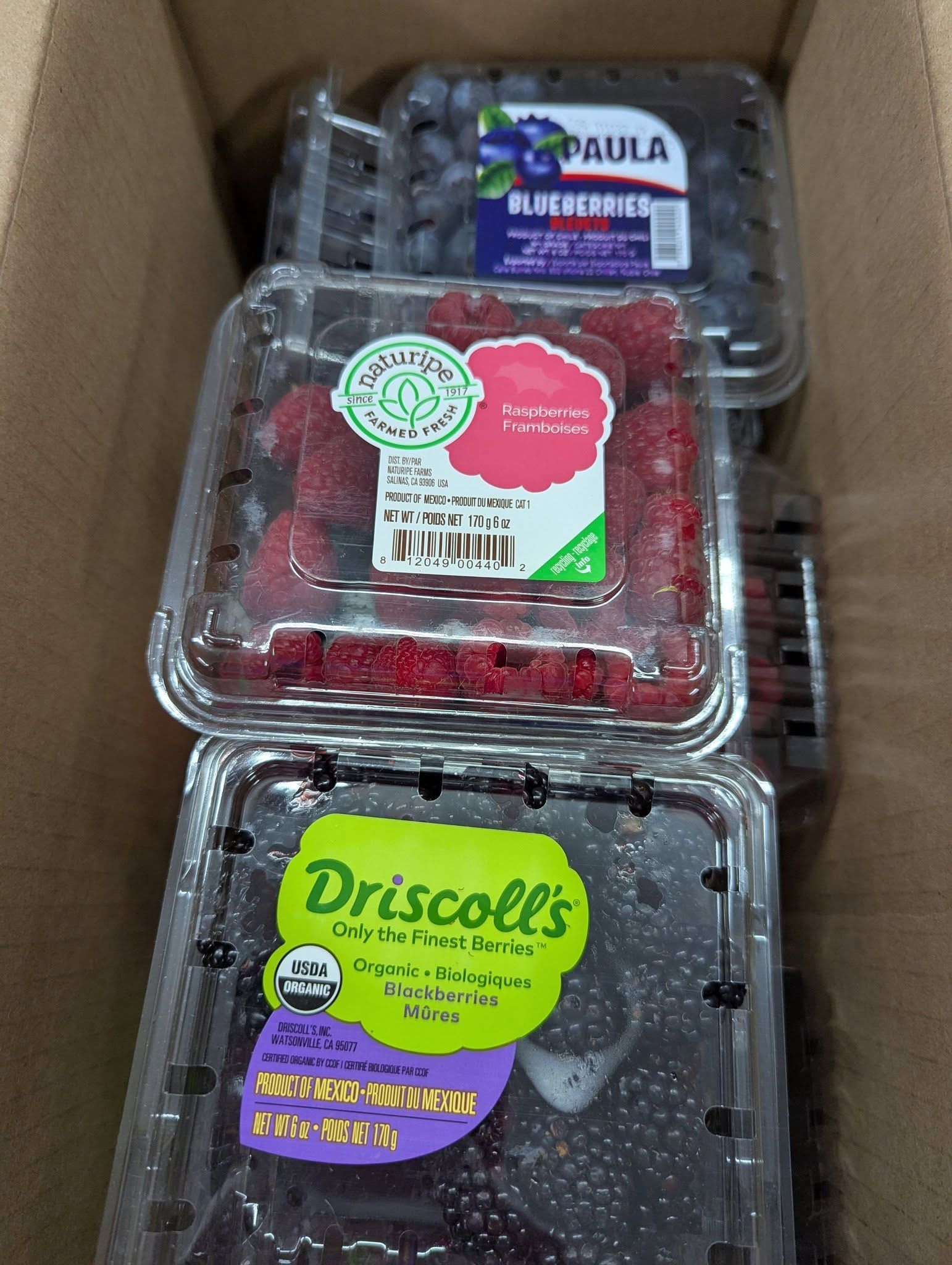 A box of berries including blueberries raspberries and driscoll 's