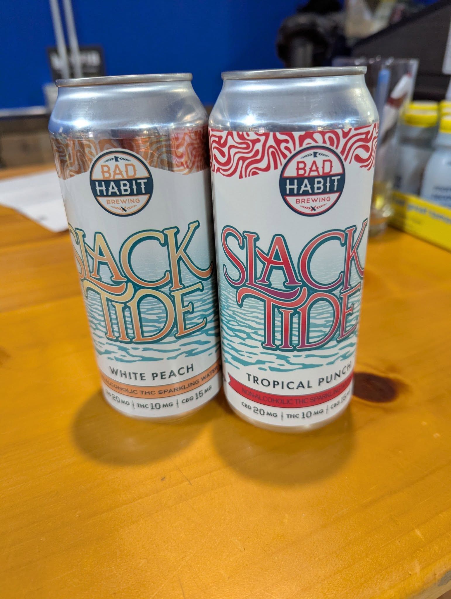 Two cans of bad habit beer are sitting on a wooden table.