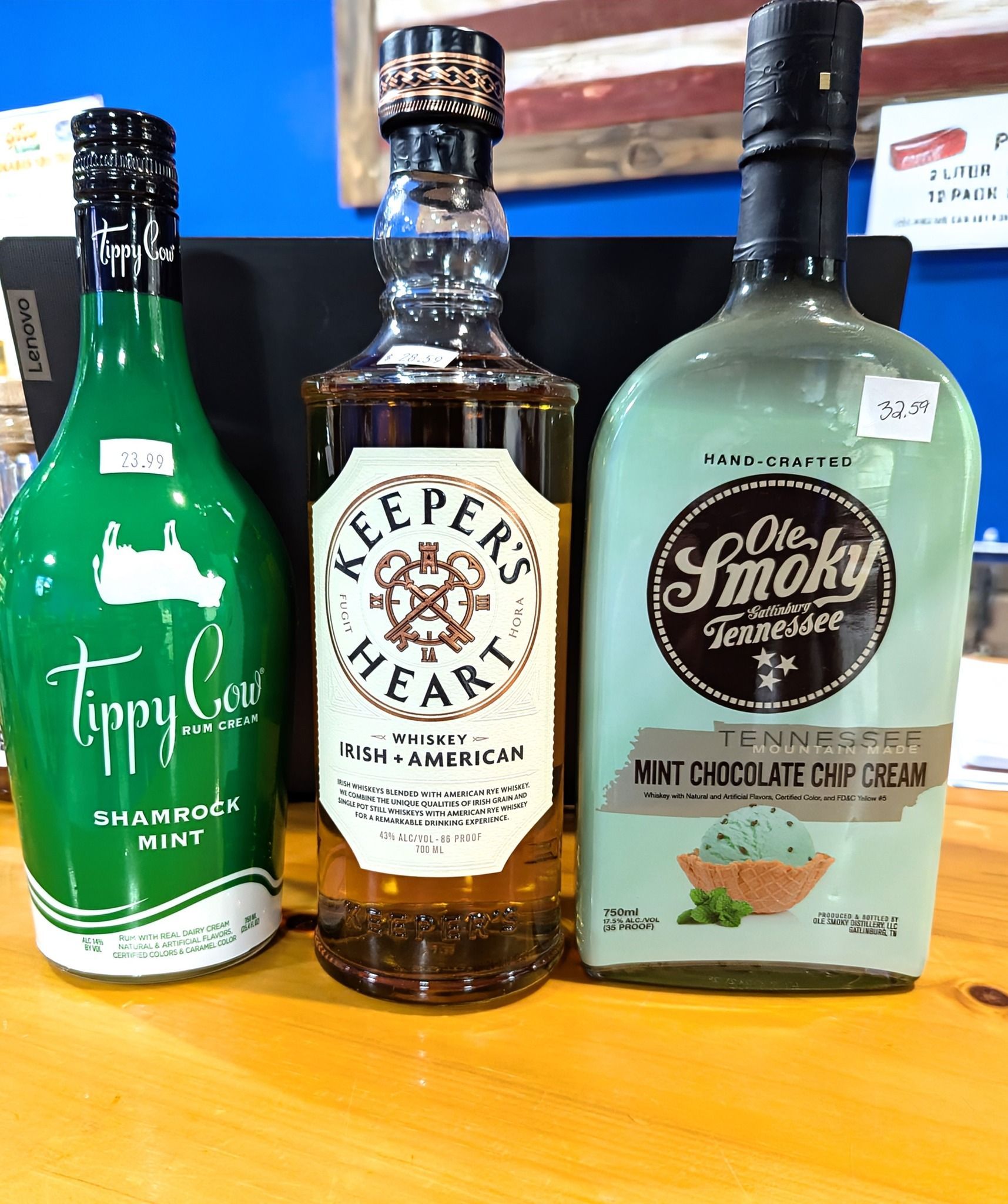 Three bottles of liquor are sitting on a wooden table.