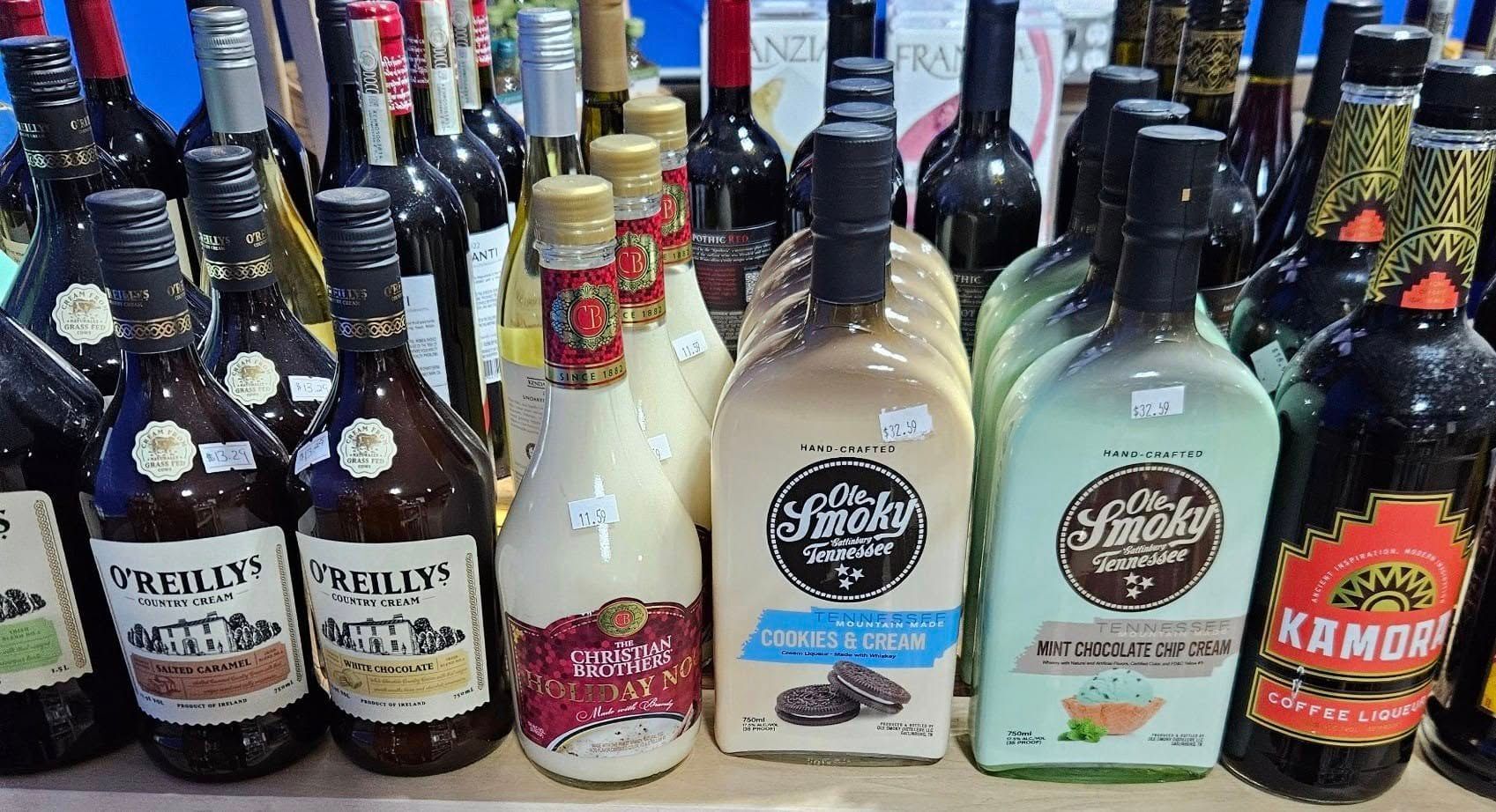 A bunch of bottles of liquor are lined up on a table.