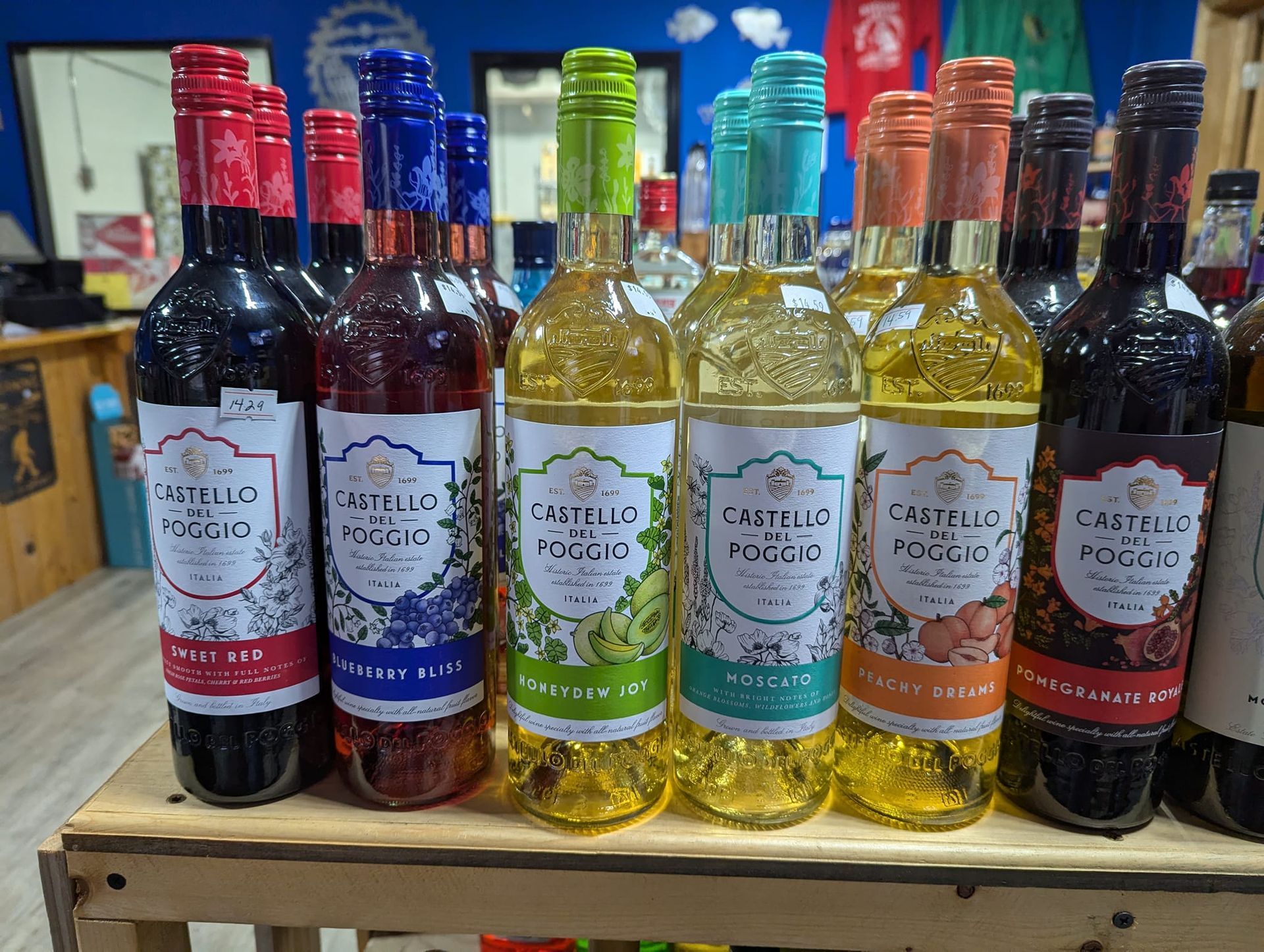 Bottles of wine are lined up on a wooden shelf in a store.
