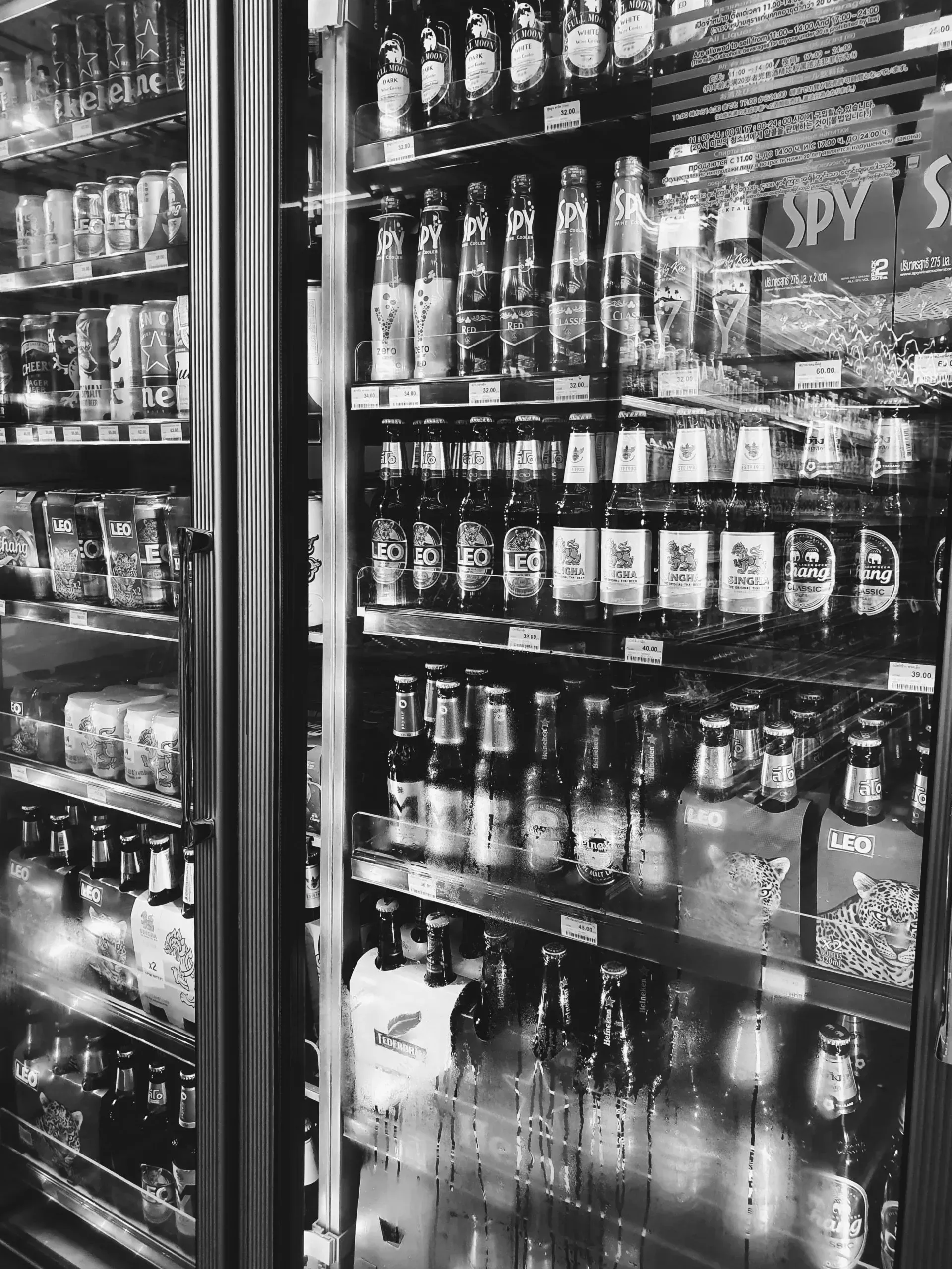 A black and white photo of a refrigerator filled with bottles of beer.