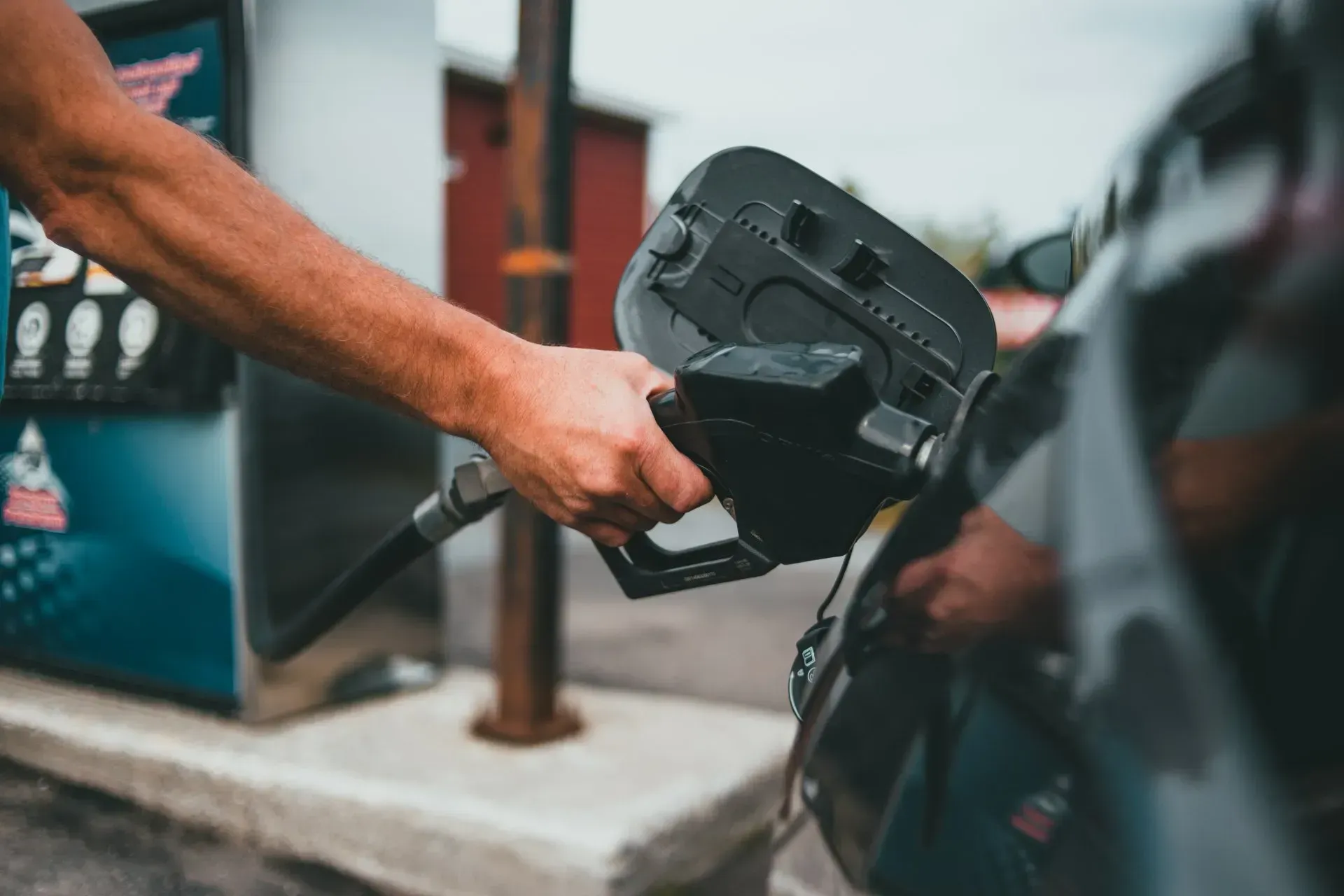 A man is pumping gas into a car at a gas station.