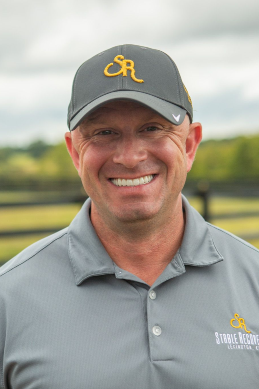 A woman with long brown hair is standing in front of a sign that says in k