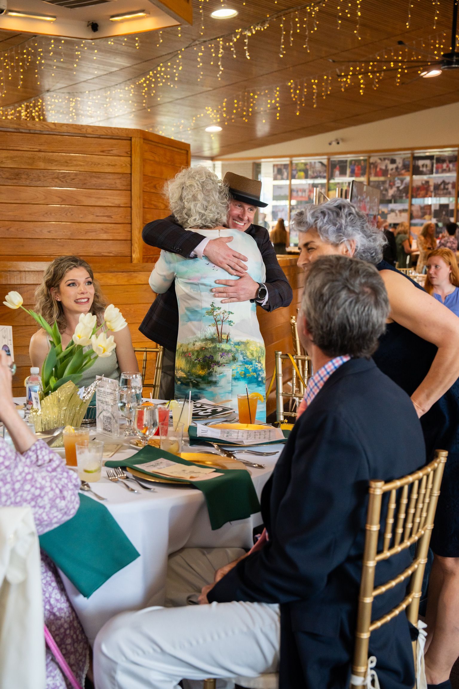 A man hugs a woman while people sit at a table.