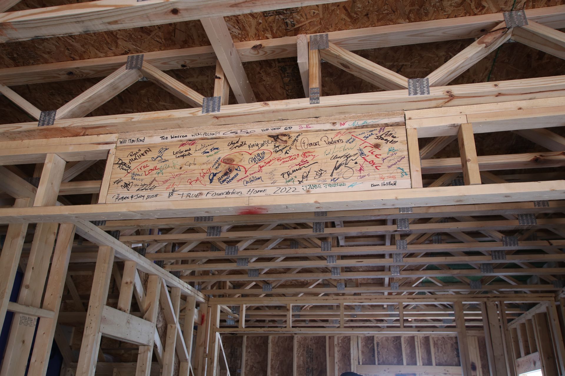 A wooden frame of a house under construction with a sign on the ceiling.