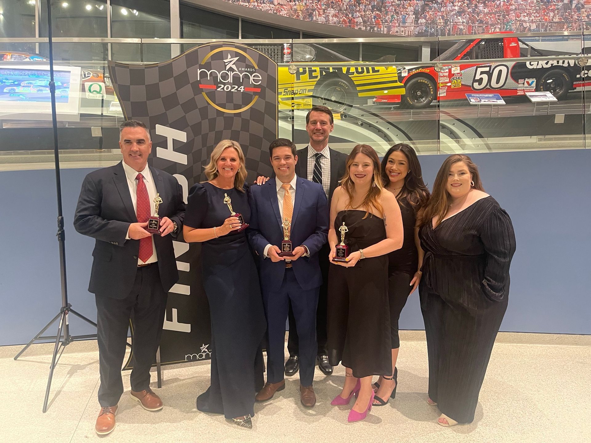 A group of people are posing for a picture in front of a race car.