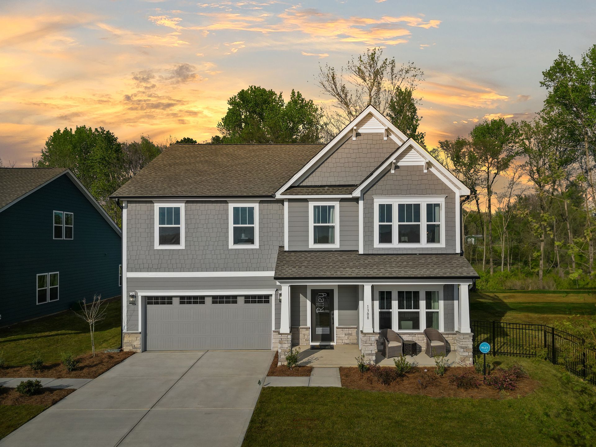 A large house with a lot of windows and a garage is sitting on top of a lush green field.