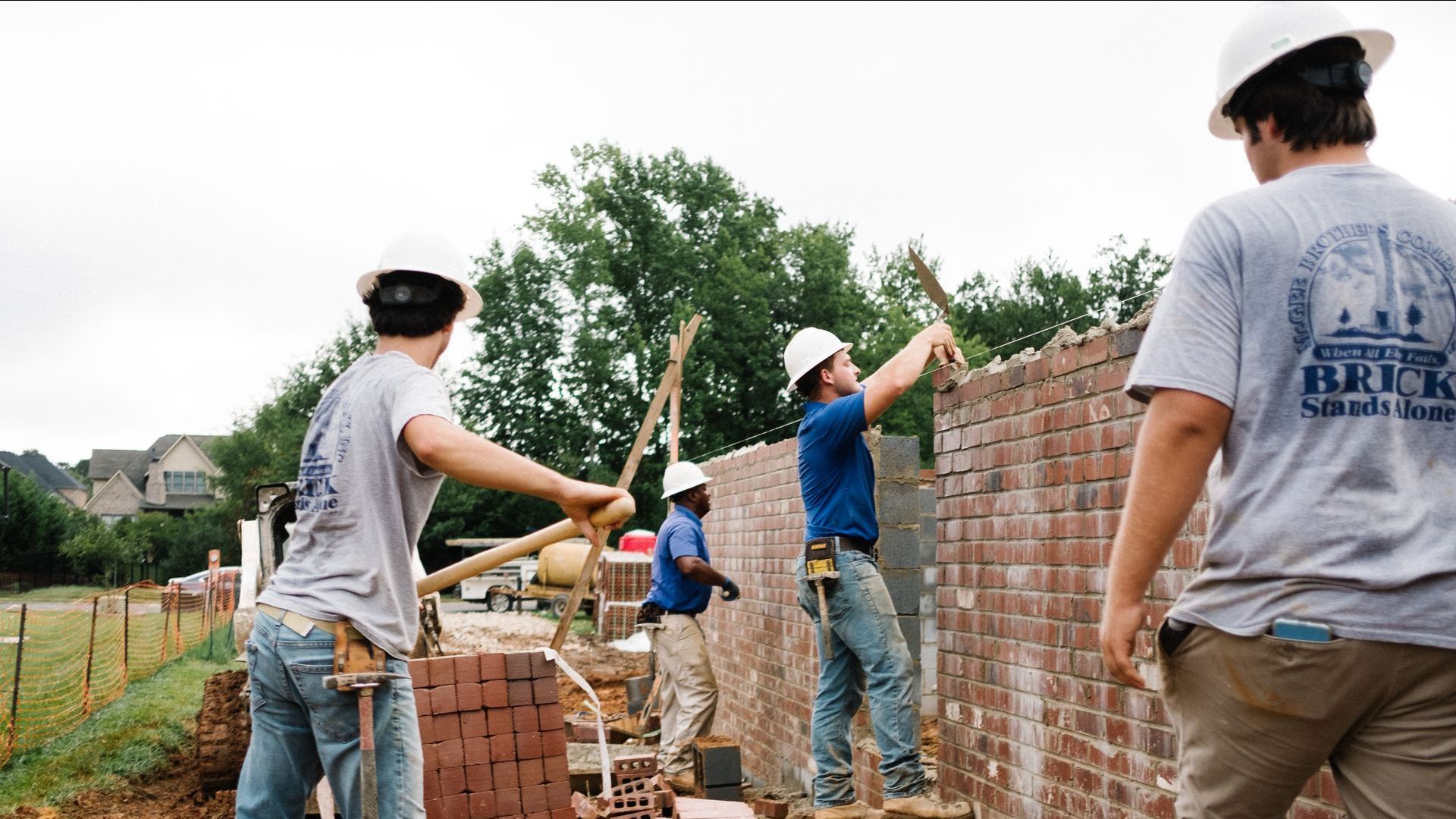 A group of construction workers are working on a brick wall.