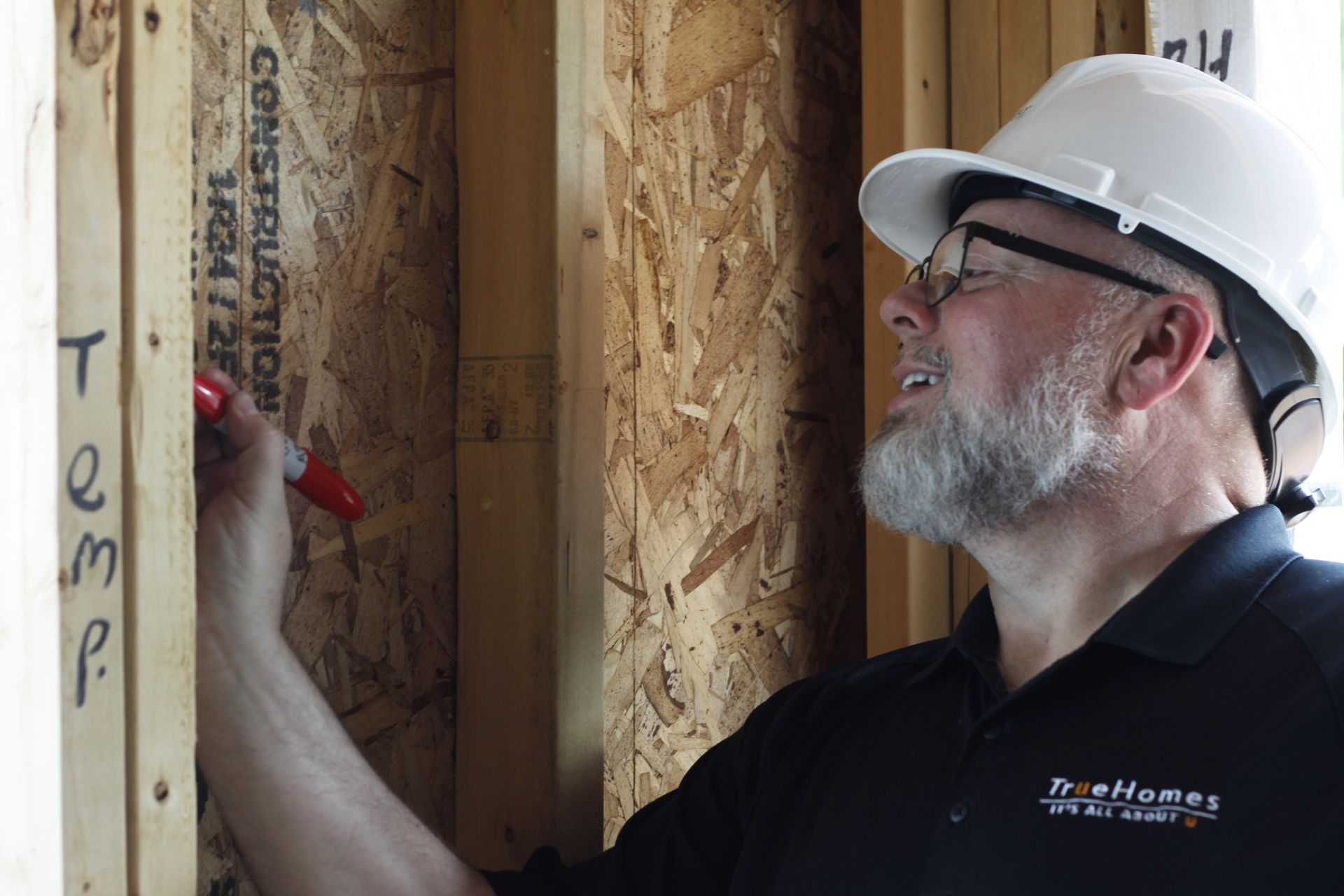 A man wearing a hard hat is writing on a wall