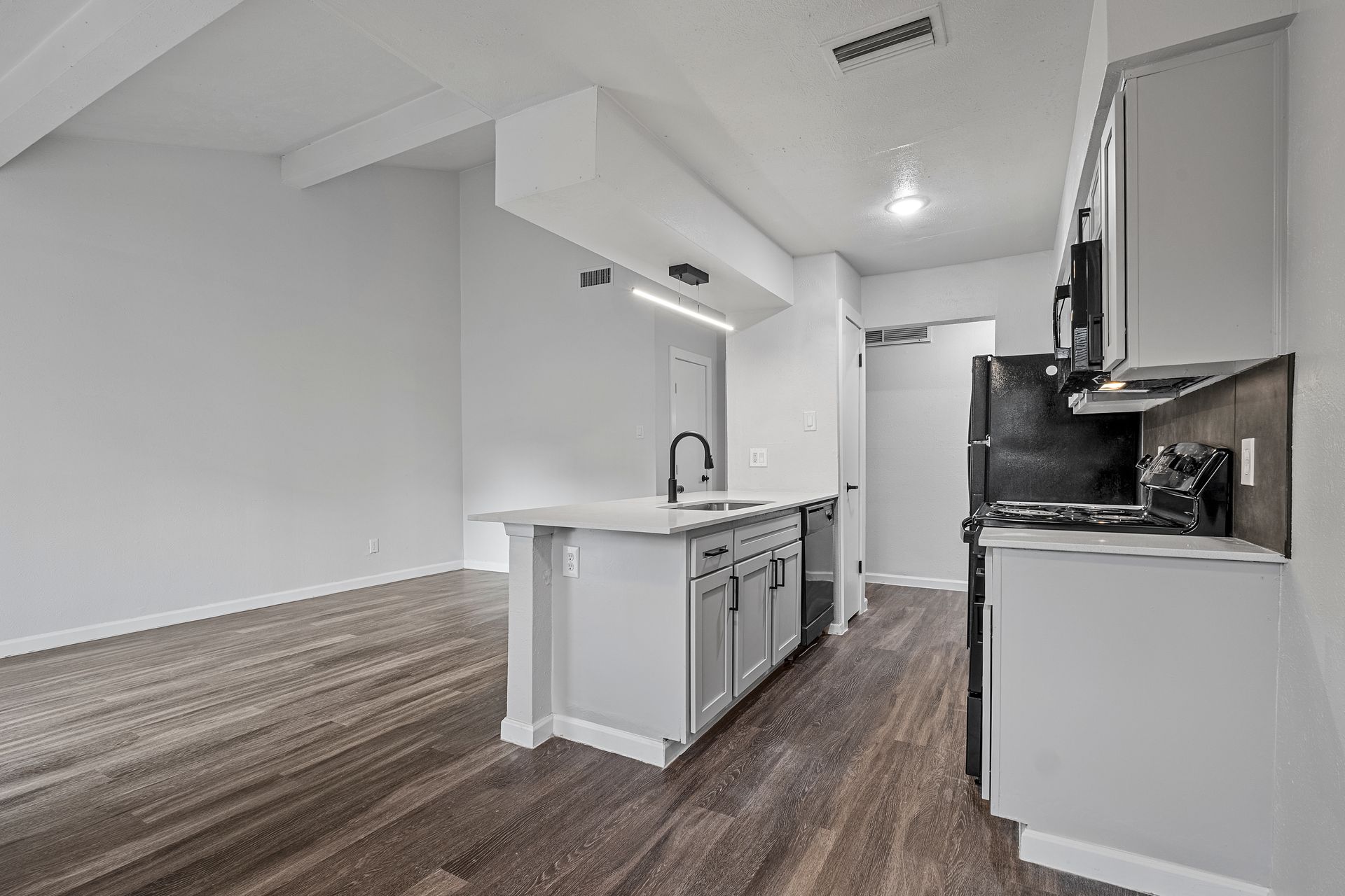Photo showing a kitchen with the living room in the background
