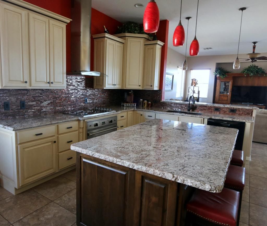 Kitchen with cream cabinets, granite countertops, and a dark wood island with red pendant lights.
