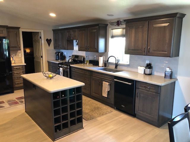 Kitchen with dark wood cabinets, light countertops, and an island with wine storage.